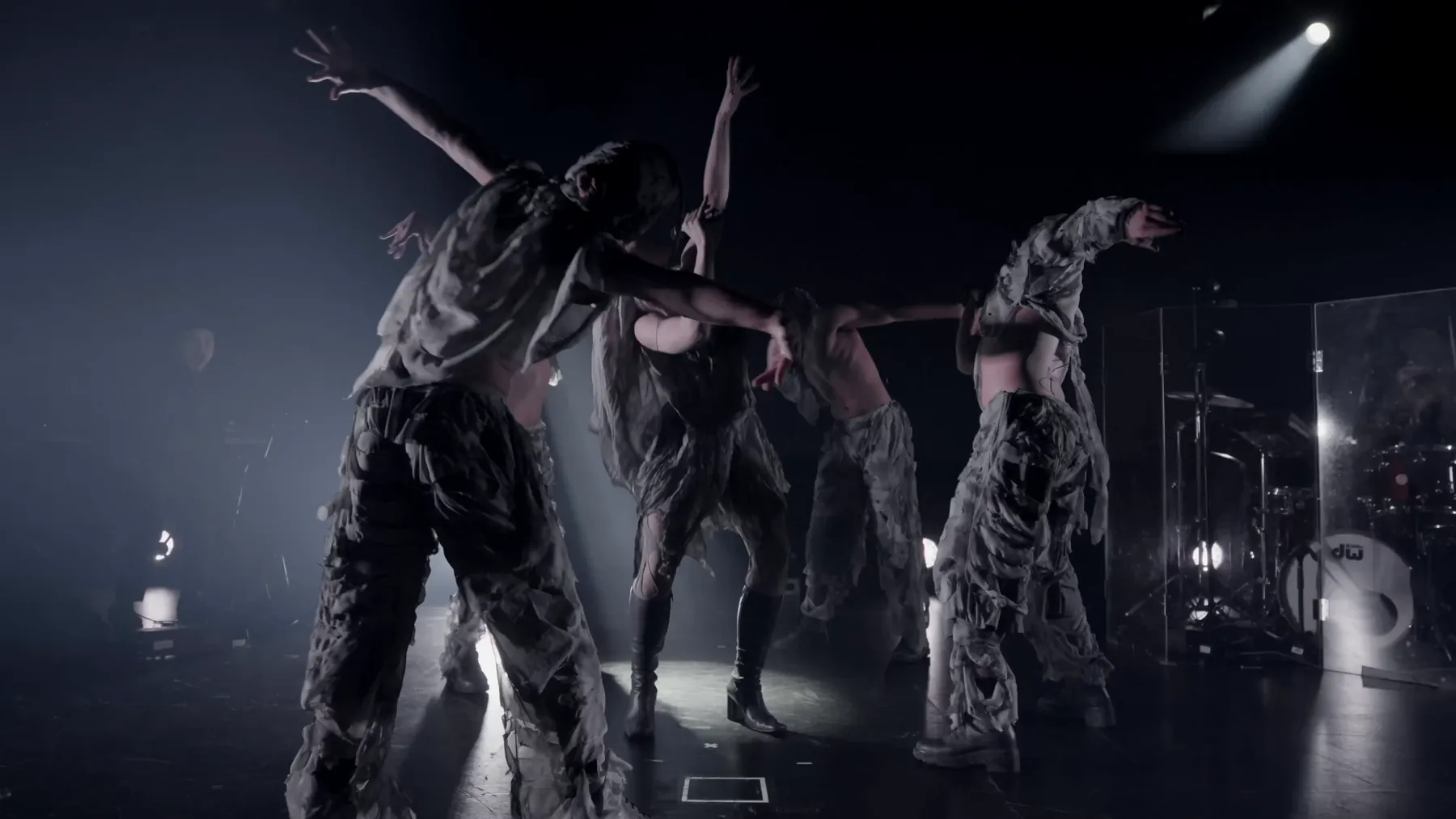 Dancers in grey costumes under white light on stage