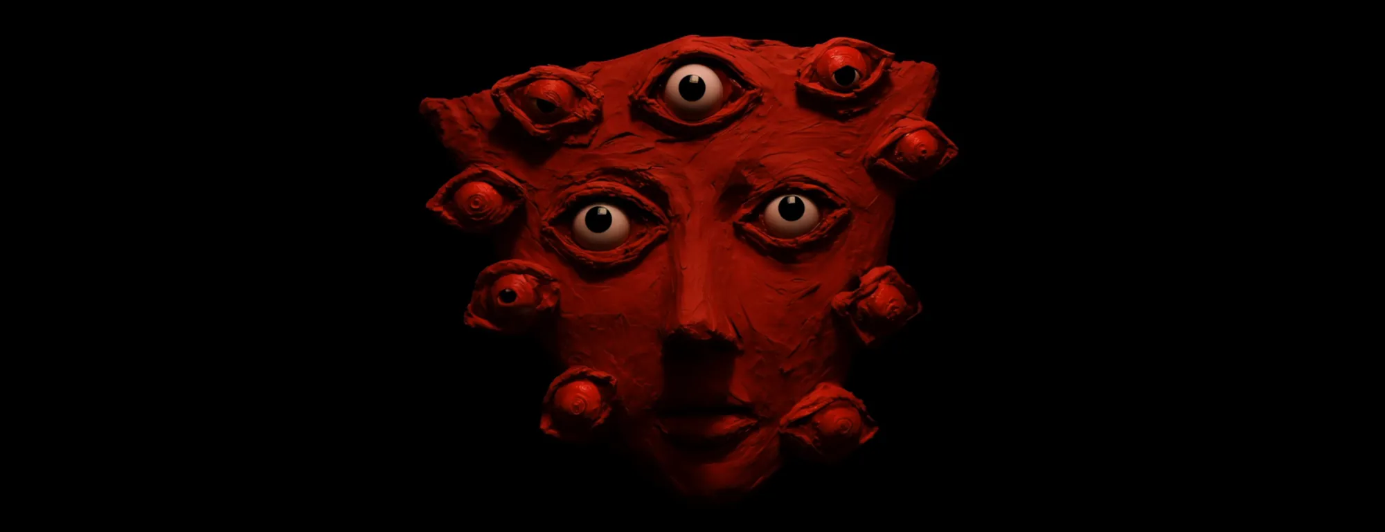 Screen content: a red sculpted face covered in eyes