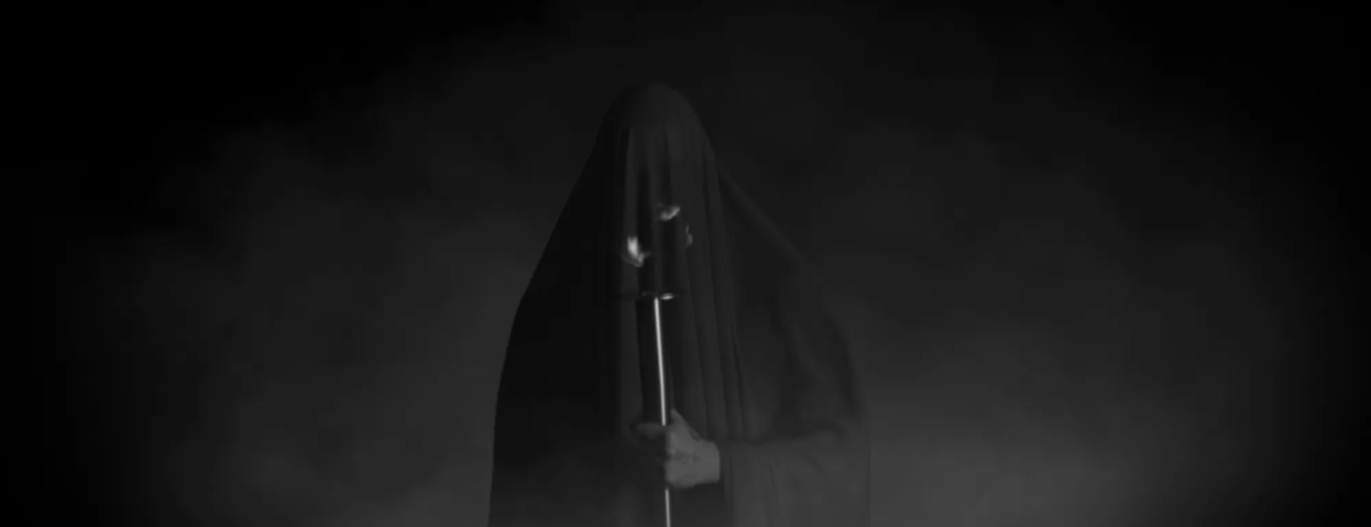 Screen content: a hooded grey figure in the dark